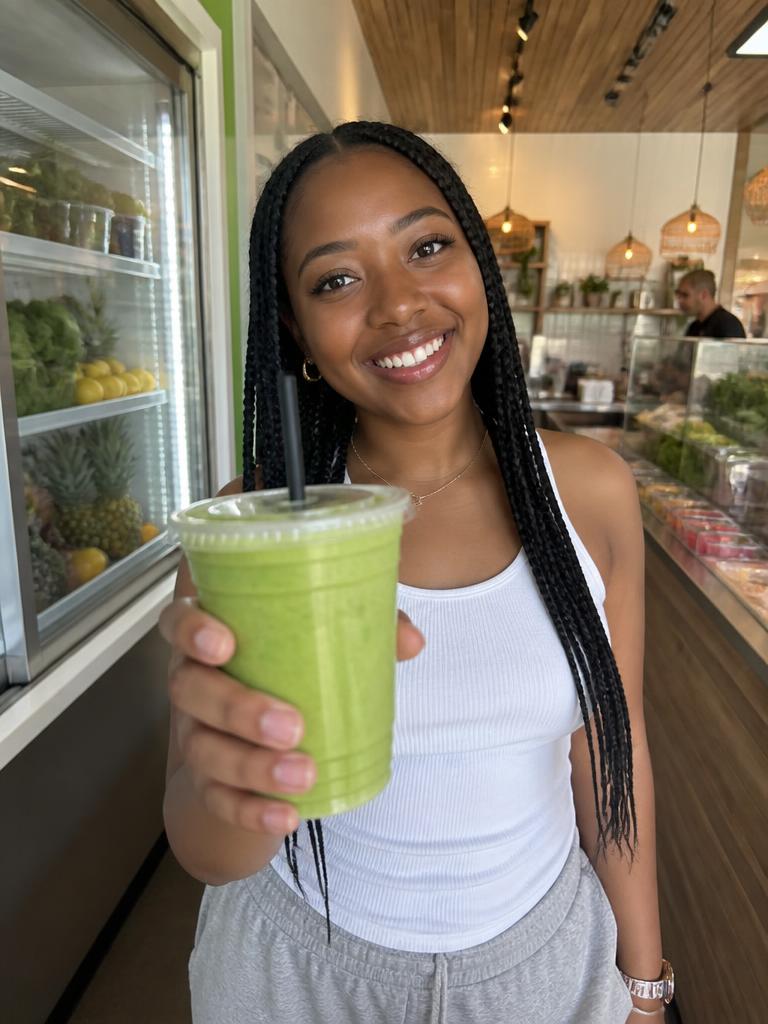 Creator holding a fresh smoothie inside a smoothie shop